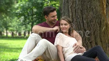 幸福的怀孕夫妇坐在公园里，<strong>计划</strong>有<strong>保障</strong>的家庭生活，福利